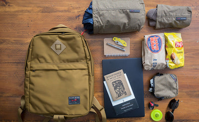 lifestyle visible^^Guide's Edition Paragon in Coyote with various items around it: a sub sandwich, chips, two books, a Pinebook Pro laptop.