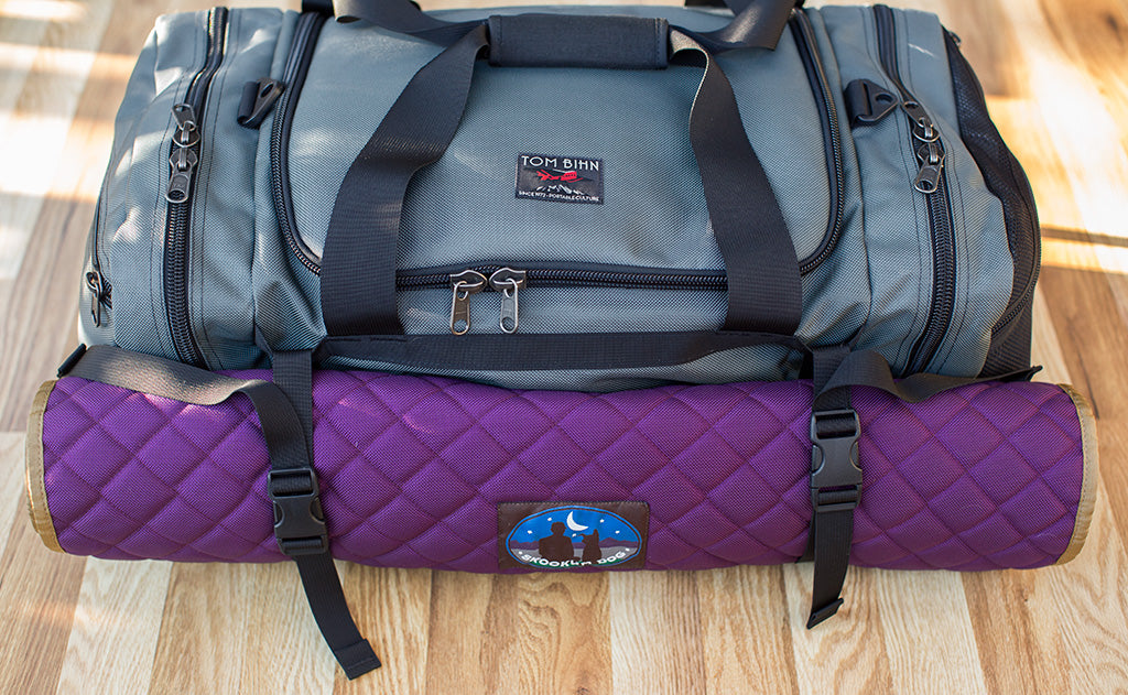 lifestyle visible^^The Road Buddy Lash Straps holding a rolled Skookum Dog Camp Mat on a Road Buddy Duffel 60.