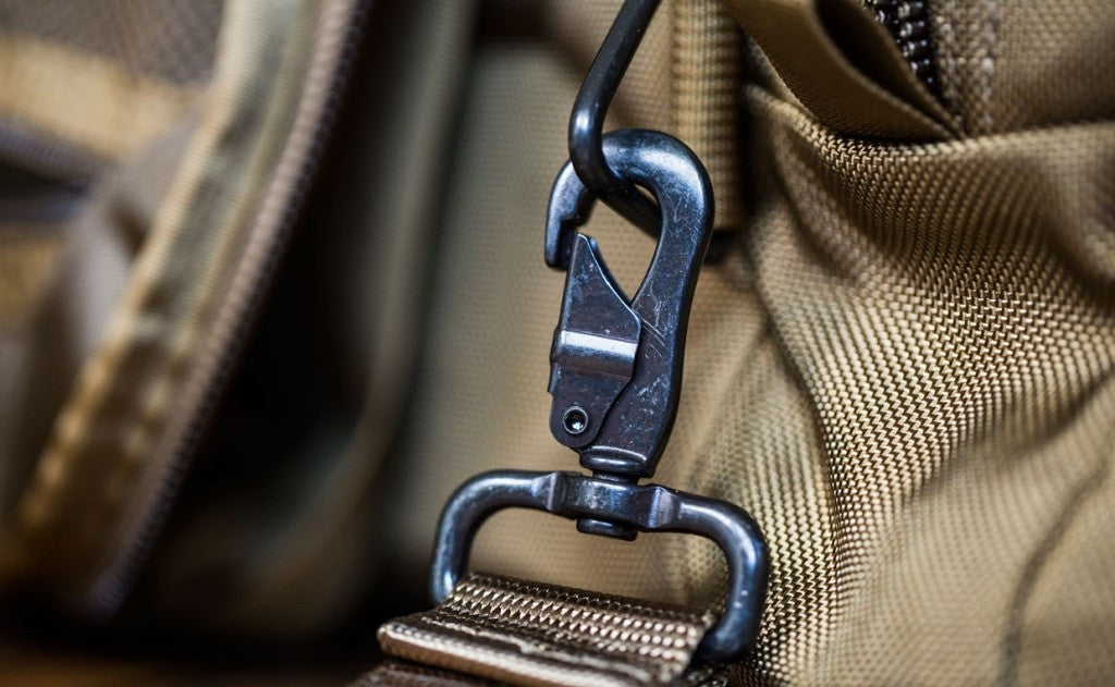 detail visible^^A close shot of a metal snaphook attached to the metal triangle attachment point on a Medium Road Duffel.