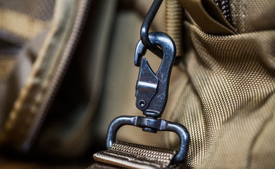 detail visible^^A close shot of a metal snaphook attached to the metal triangle attachment point on a Medium Road Duffel.
