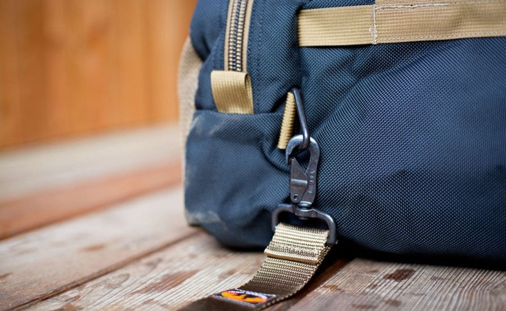 detail visible^^A close shot of a metal snaphook attached to the metal triangle attachment point on a Large Road Duffel.