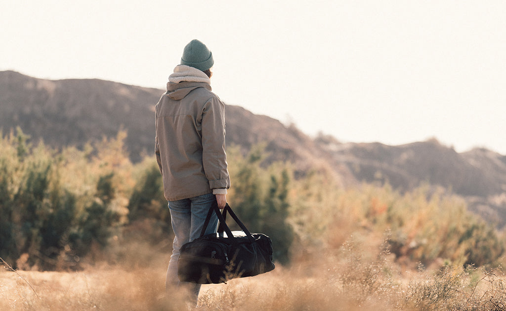 lifestyle visible^^A person carrying the Road Buddy Duffel 60 via the padded carry handle.