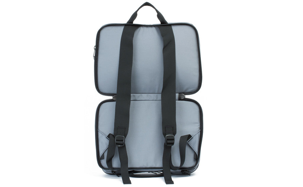 visible variant TB0975-LKLJ^^The Stowaway in Cloud (light grey) 525 Ballistic with the center compartment open to access the backpack straps.