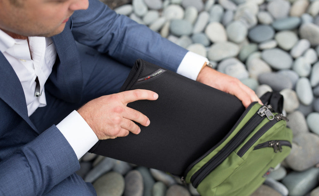 lifestyle visible^^A person putting their laptop in the rear main pocket of The Stowaway.