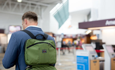 lifestyle visible^^A person carrying The Stowaway via backpack straps in an airport.