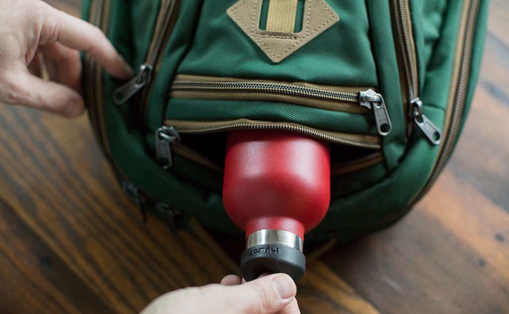detail visible^^A person sliding a water bottle in to the water bottle pocket of the Guide's Edition Synik 22.