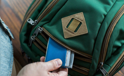 detail visible^^A person retrieving a wallet from the small front pocket on the Guide's Edition Synik 22.