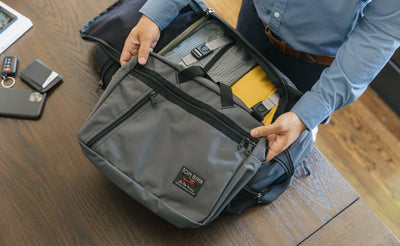 lifestyle visible^^A person packing an empty Nebulous Grey Daylight Briefcase inside a Techonaut travel bag.