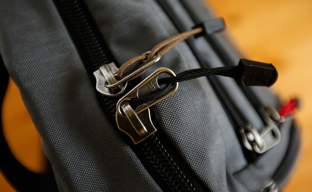 visible variant TB0512A-CA TB0512A-BA^^Cord Zipper Pulls with plastic pull tabs attached to a bag's metal pull tabs.