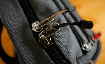 visible variant TB0512A-CA TB0512A-BA^^Cord Zipper Pulls with plastic pull tabs attached to a bag's metal pull tabs.