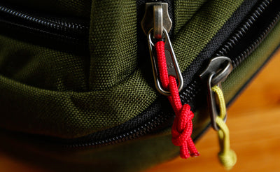 visible variant TB0512C-IA TB0512C-WA^^Cord Zipper Pulls knotted and attached to a bag's metal pull tabs.