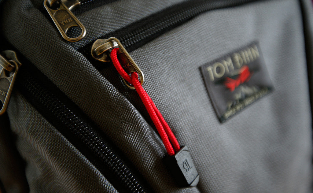 visible variant TB0512A-IA^^Cord Zipper Pulls with plastic pull tabs attached to a bag's metal pull tabs.