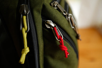visible variant TB0512B-WA TB0512B-IA TB0512C-WA TB0512C-IA^^Cord Zipper Pulls knotted and attached to a bag's metal pull tabs.