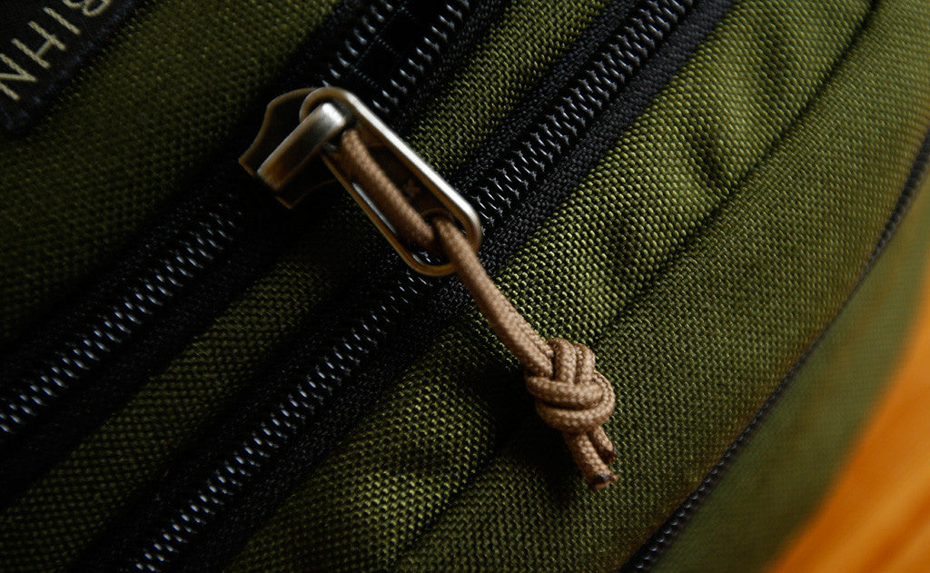 visible variant TB0512C-CA^^Cord Zipper Pulls knotted and attached to a bag's metal pull tabs.