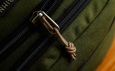 visible variant TB0512C-CA^^Cord Zipper Pulls knotted and attached to a bag's metal pull tabs.