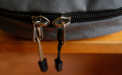 visible variant TB0512A-CA TB0512A-BA^^Cord Zipper Pulls with plastic pull tabs attached to a bag's metal pull tabs.