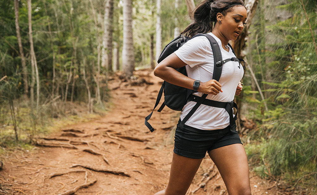 visible lifestyle^^Woman jogging down a hiking trail wearing the Shadow Guide 33 with the sternum and waist belts fastened.