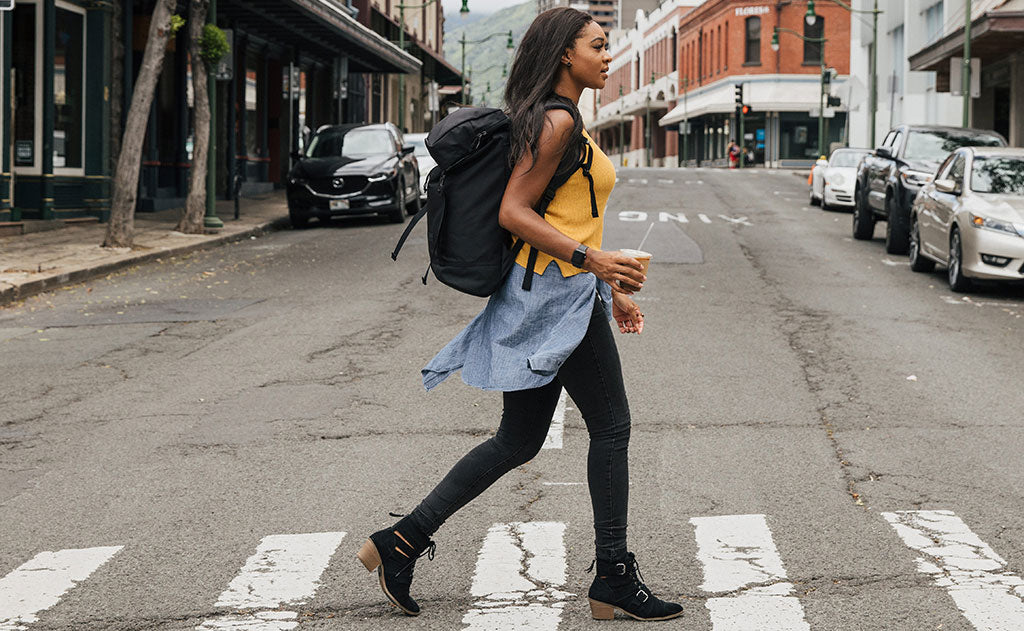 lifestyle visible^^Woman crossing the street while carrying an iced coffee drink and wearing the Shadow Guide 33.