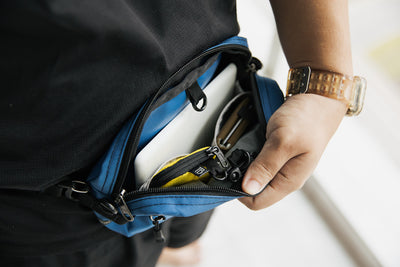 lifestyle visible^^Person opening the main pocket of their Side Effect while wearing it as a hip bag