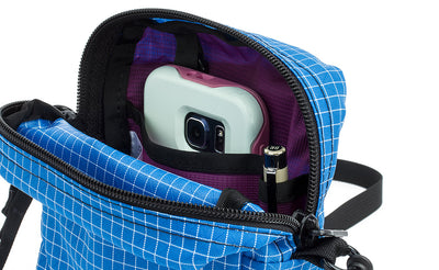 ^^Travel Cubelet zipped open showing the interior open-top organizer pockets with a phone in the larger pocket and a pen in the pen pocket.