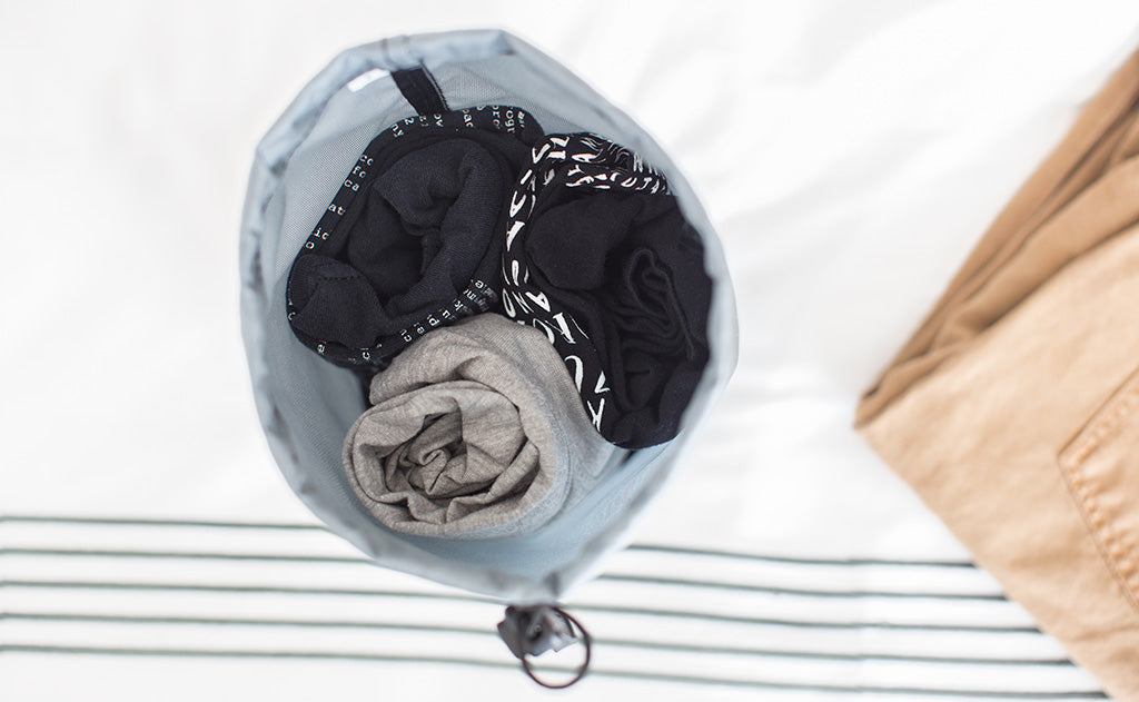lifestyle visible^^A Travel Stuff Sack holding 3 rolled up shirts.