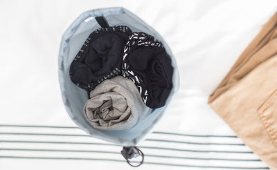 lifestyle visible^^A Travel Stuff Sack holding 3 rolled up shirts.
