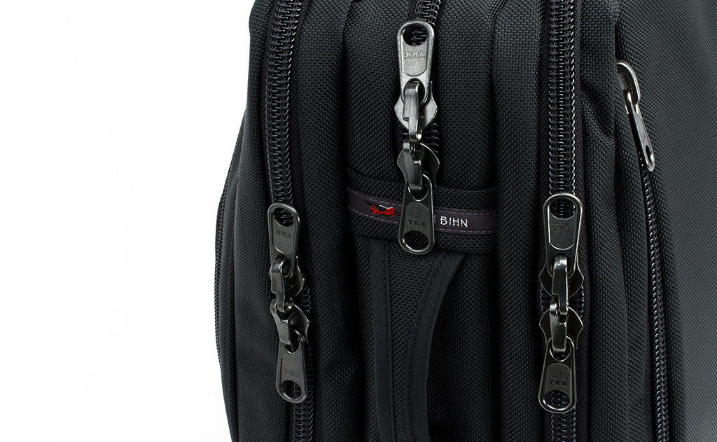 detail visible^^A close shot from a profile point of view of the three main pockets and their locking zippers as well as a side grab handle.