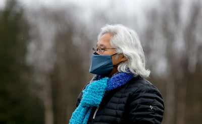 visible variant ME00012-LO^^Person wearing the V6 Mask in Pacific Blue outdoors. The person is wearing glasses, a blue knitted scarf, and a puffy jacket.