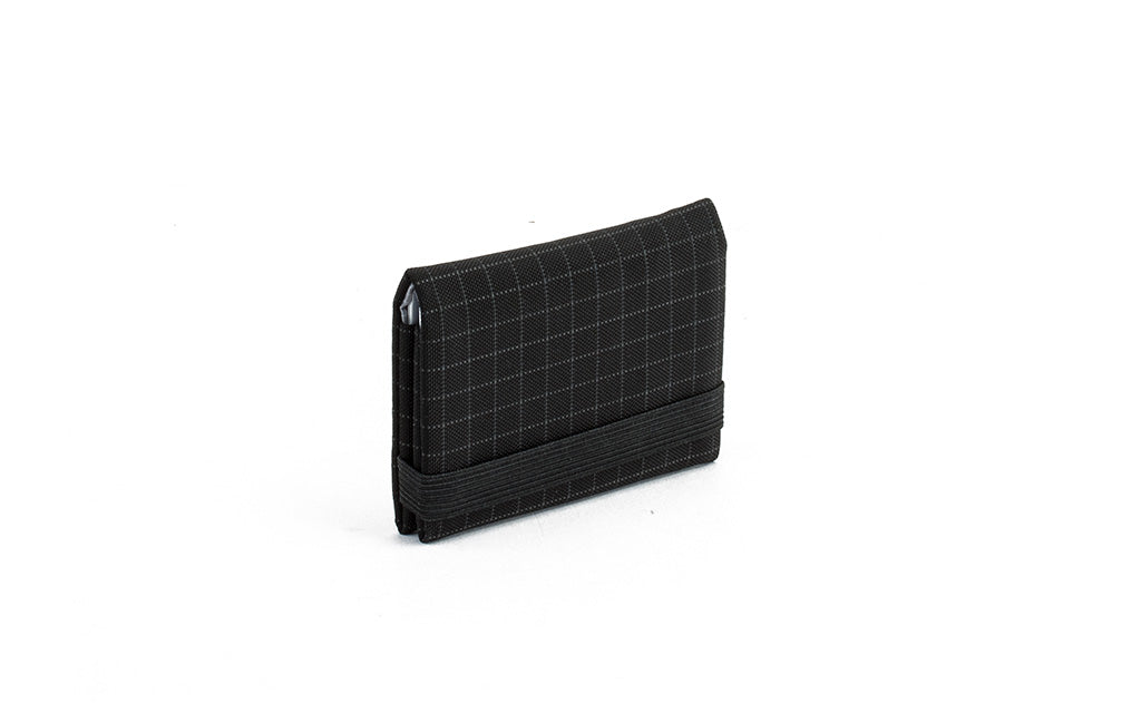 visible variant TB1277-BH^^The Size 1 Nik's Minimalist Wallet in Black (black with grey grid) 400 Halcyon closed with the attached elastic band.