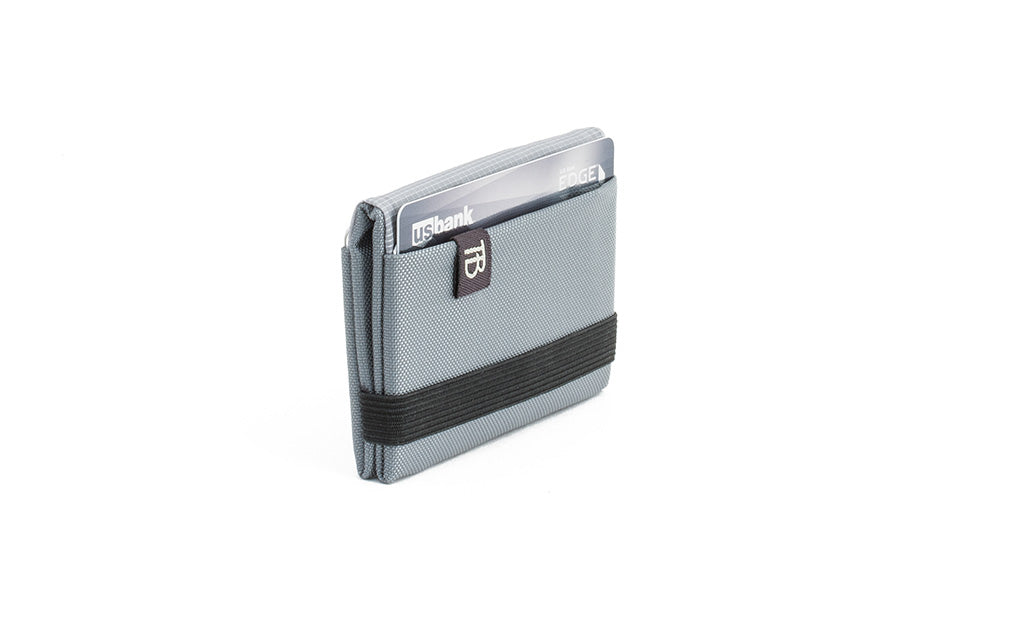 visible variant TB1277-LJ^^The Size 1 Nik's Minimalist Wallet in Cloud (light grey) 210 Ballistic closed pockets-out with the attached elastic band.
