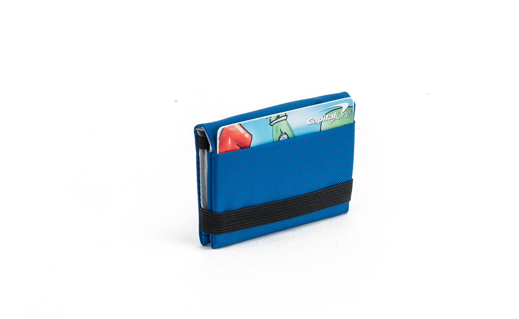 visible variant TB1279-IJ^^The Size 3 Nik's Minimalist Wallet in Island (blue) 210 Ballistic closed with the attached elastic band.