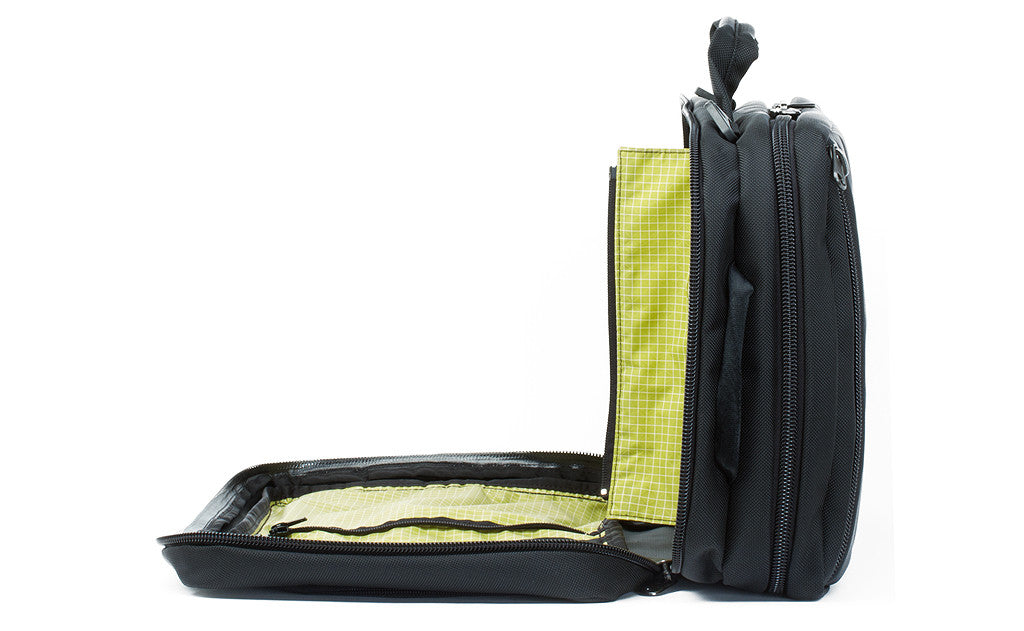 ^^A profile shot of the front pocket of a Black 525 Ballistic exterior open showing the Wasabi (green) 200 Halcyon interior's zippered divider unzipped.