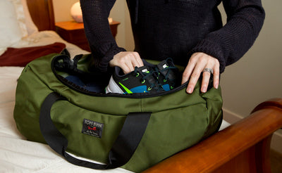visible lifestyle ^^ A person packing a pair of shoes into the Medium Yeoman Duffel.