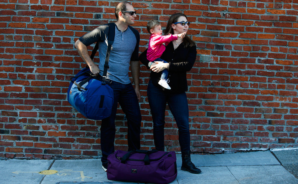 lifestyle visible ^^ A person carrying a Yeoman Duffel with a shoulder strap, and another person carrying a child with another Yeoman at their feet.