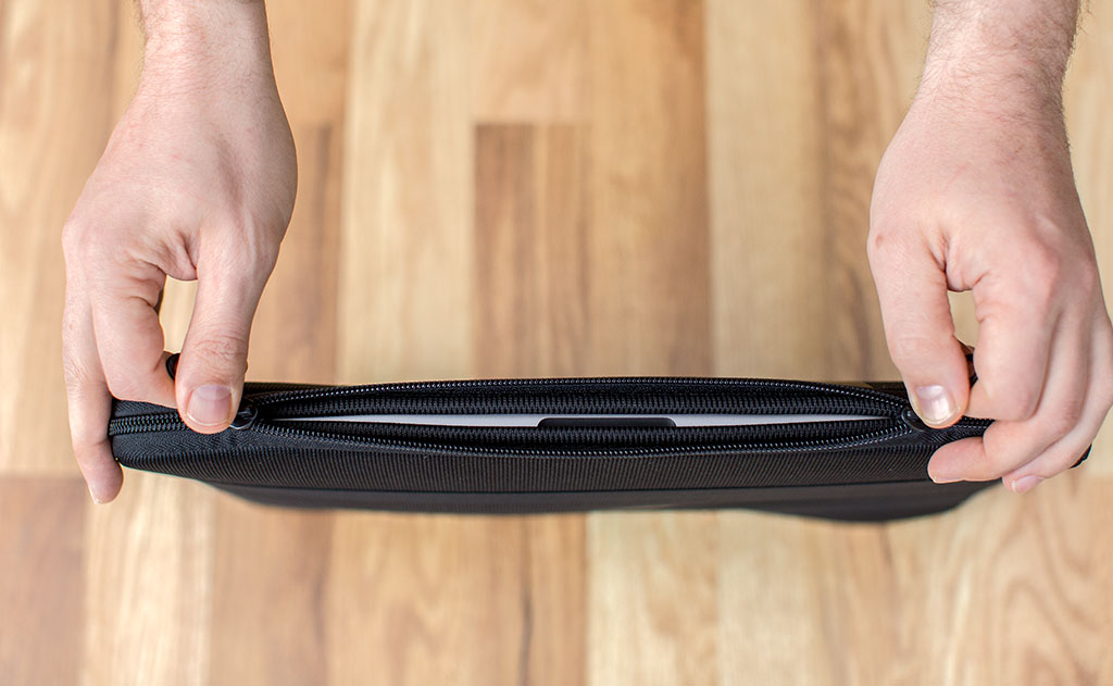 detail visible^^A laptop in a Cache being opened on the horizontal zipper side.