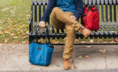detail visible^^Person sitting on a bench with Shop Bags next to them.