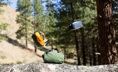 detail visible^^ a photo of a Boreal Grab Bag on a rock with a Texturized Orange and Faded Leopard Print Vinyl Grab Bag tossed in the air. 