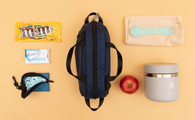 detail visible^^ A Navy Parapack Grab Bag with lunch and snack items on either side. 