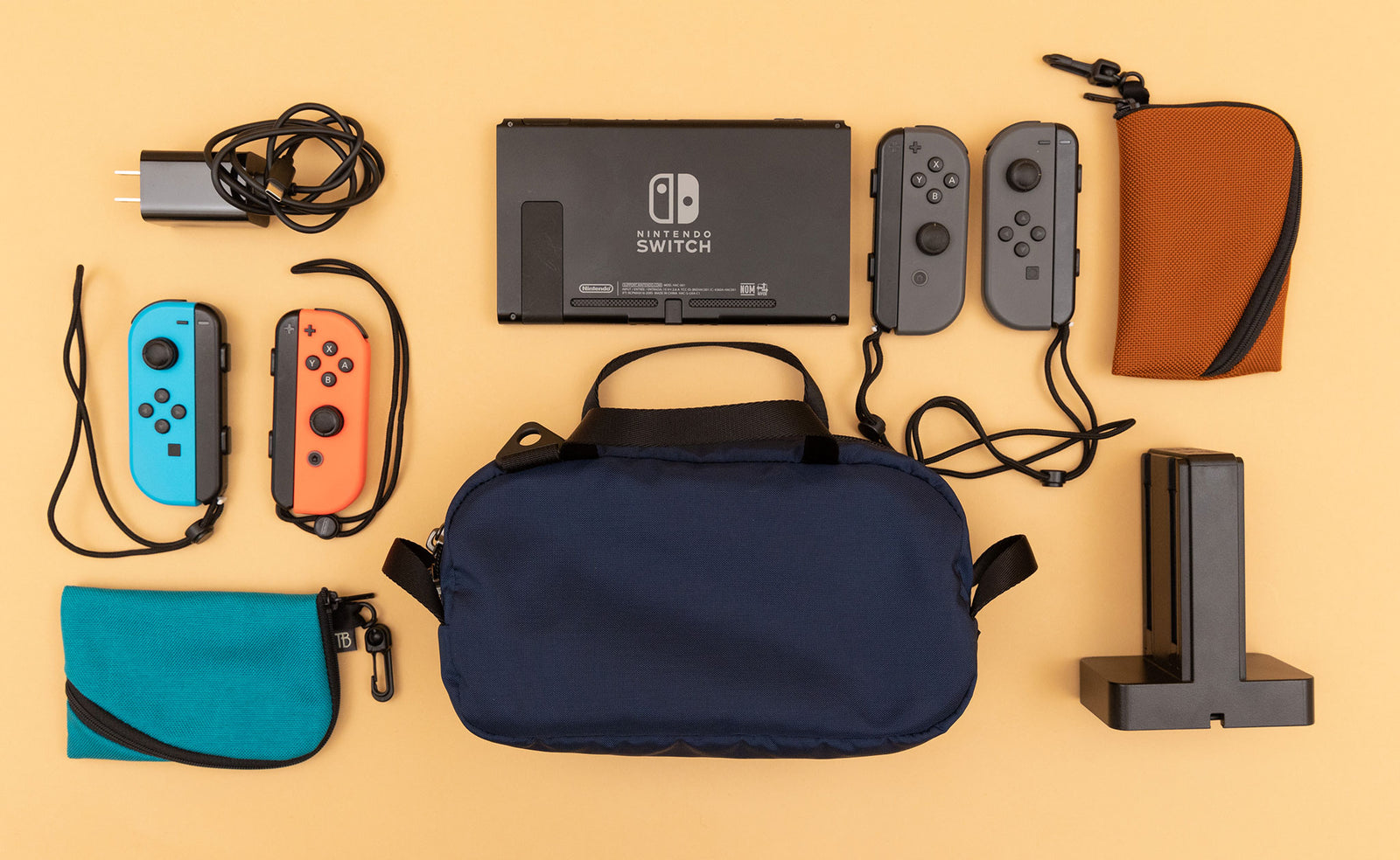 detail visible^^ A Navy Parapack Grab Bag with Nintendo Switch and accessories next to it, including two Mini Ghost Whale Pouches. 