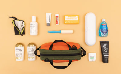 detail visible^^ a Texturized Orange Grab Bag with various travel toiletry items next to it. 