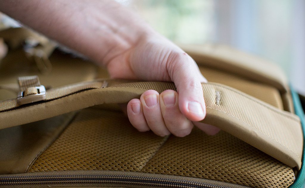 detail visible^^A person squeezing the shoulder strap of the Guide's Edition Synik 22.