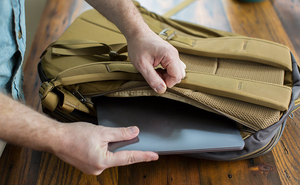 detail visible^^A person putting a laptop into the laptop compartment of the Guide's Edition Synik 30.