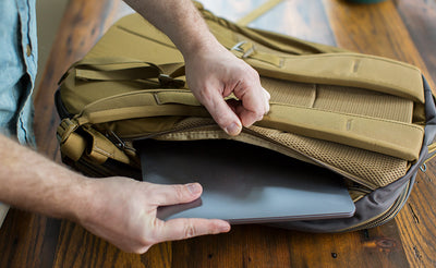 detail visible^^A person putting a laptop into the laptop compartment of the Guide's Edition Synik 30.