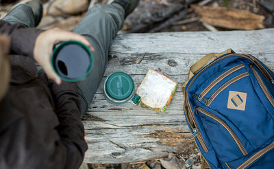 lifestyle visible^^A person having lunch on a log with a Guide's Edition Synapse 25.