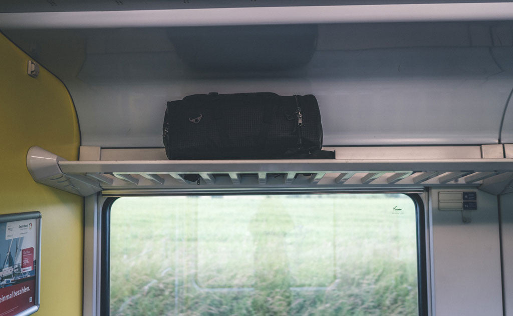 lifestyle visible^^A Hero's Journey main bag on the overhead rail of a railcar.