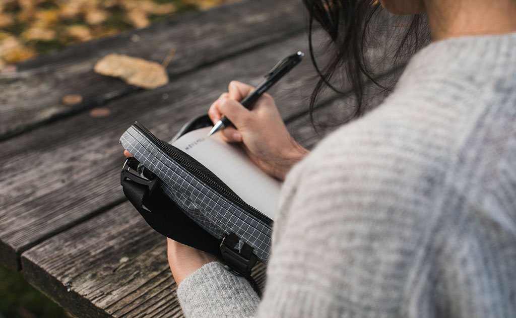 A person holding the HLT1 like a book to write in a notebook.