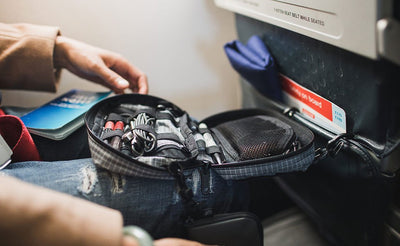 visible lifestyle ^^ A  person retrieving items from an HLT1 clipped to an airline seat pocket.