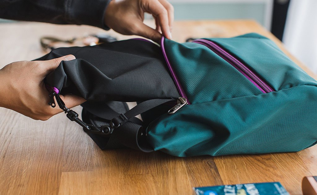 detail visible^^A person putting an organizer pouch in the main compartment of an Icon.