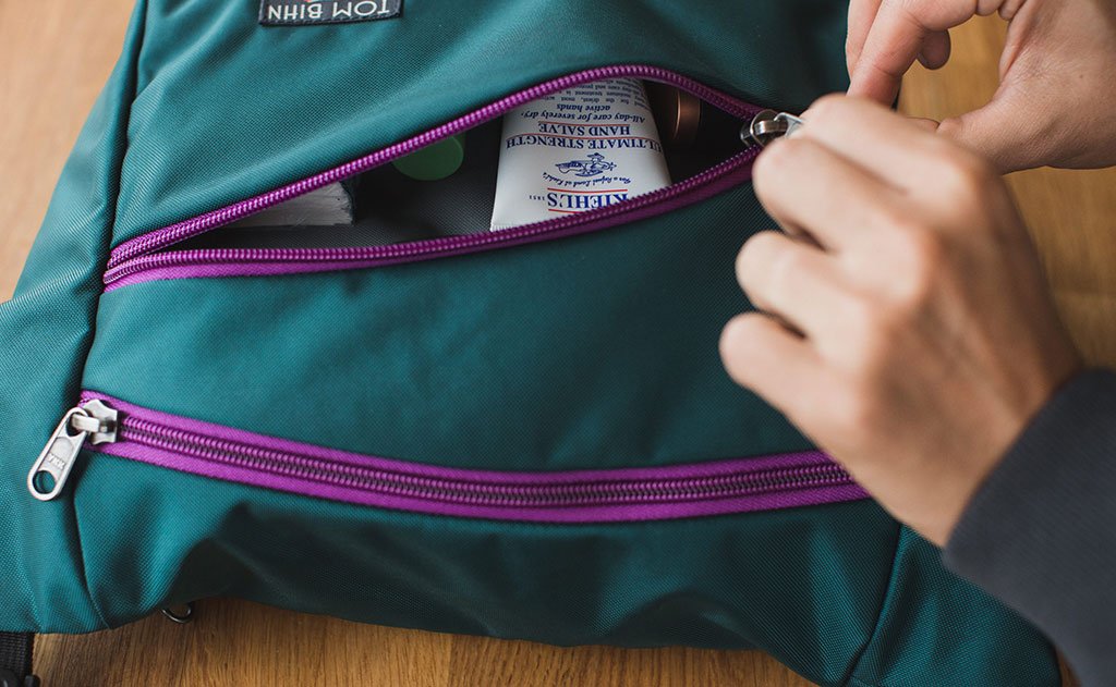 detail visible^^A person zipping up the front compartment of the Icon.