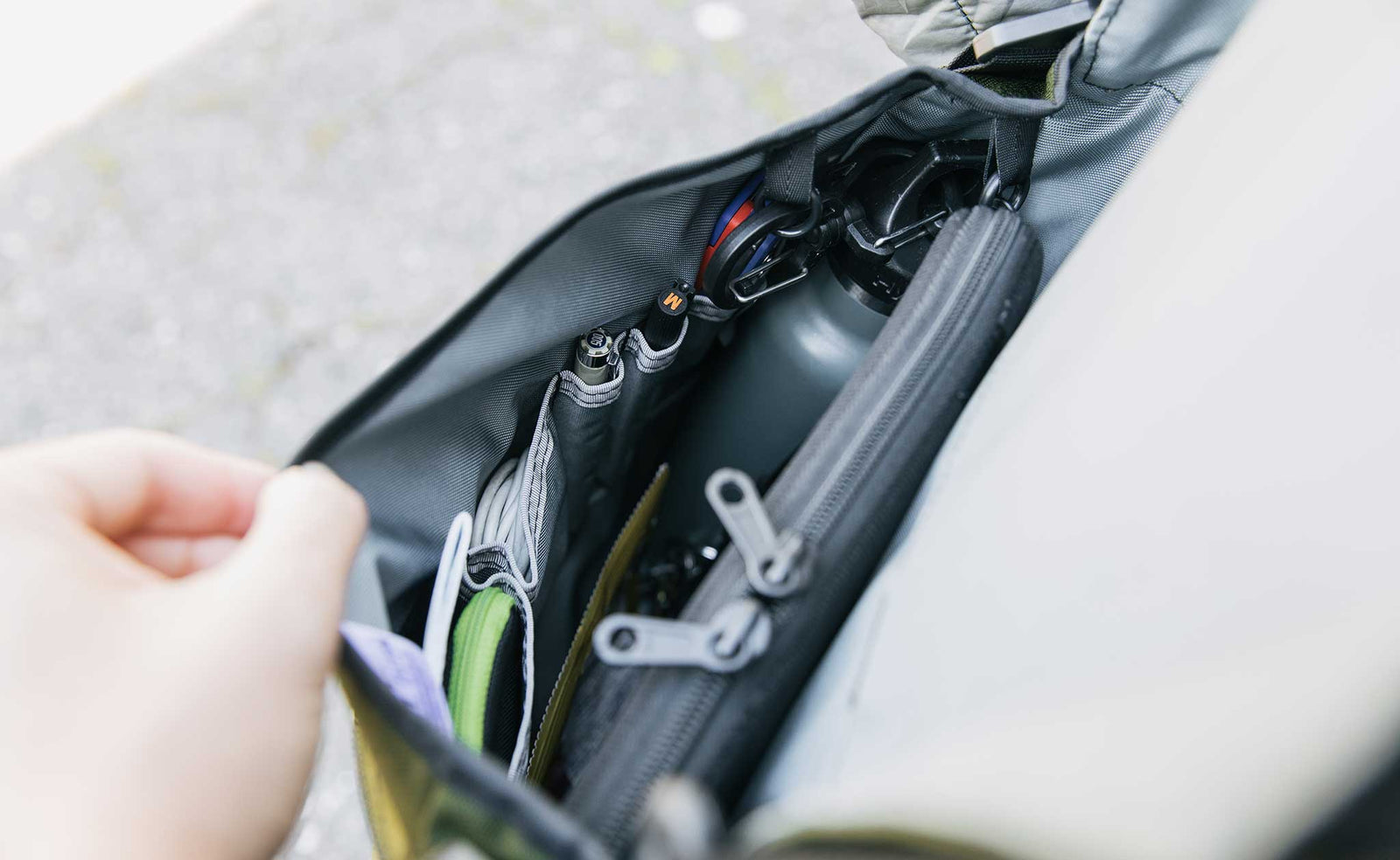 lifestyle visible^^Peering down into the main compartment of the Large Cafe Bag as a person wearing it opens it. You can see a tablet in a Cache, a water bottle, pens, pouches, etc.